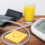orange juice on desk with post it and blood pressure checker
