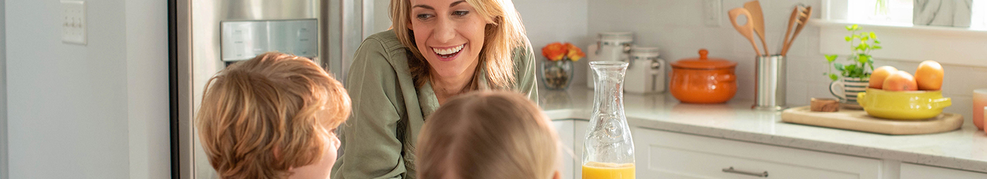 mom with kids and orange juice in kitchen